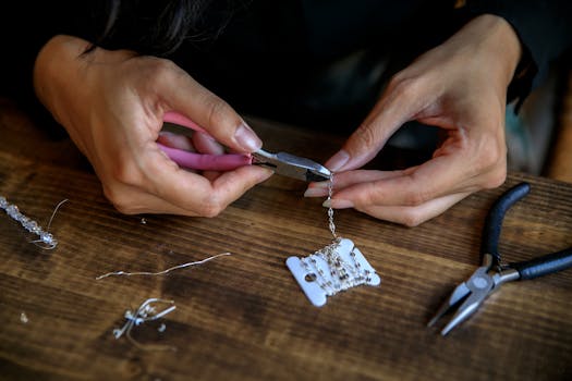 Detailed view of hands crafting jewelry using pliers, showcasing creativity and craftsmanship.